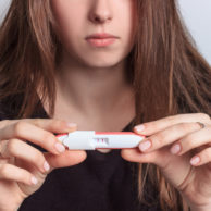 Know Your Pregnancy Options | Get Options Counseling at CWHC | patient looking at positive pregnancy test